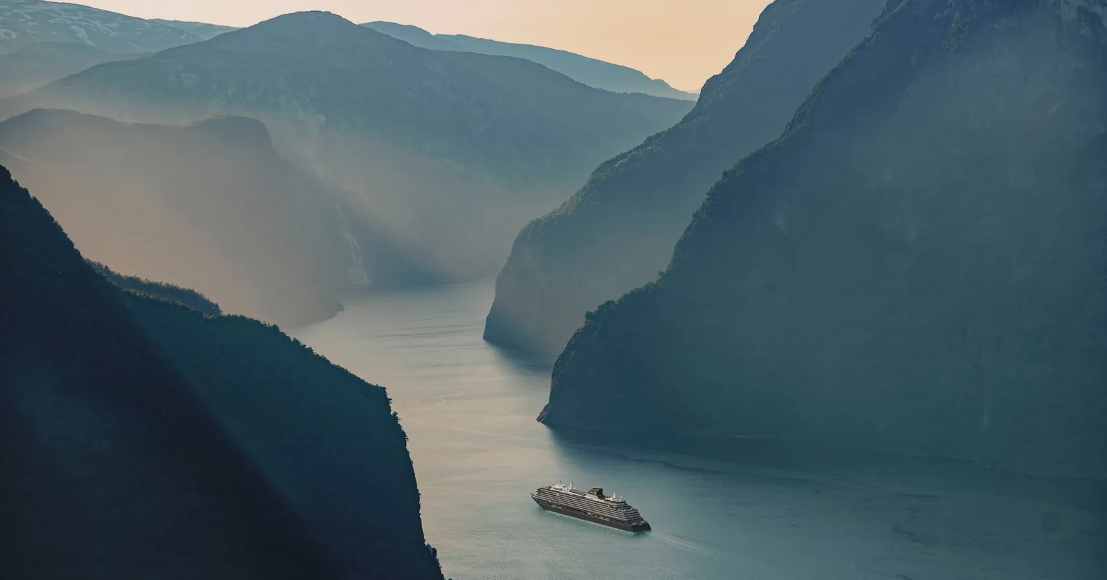 Navio navegando por um fiorde entre montanhas
